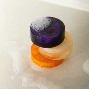 From above of assorted colorful handmade soaps with froth flow and tiny bubbles on white background