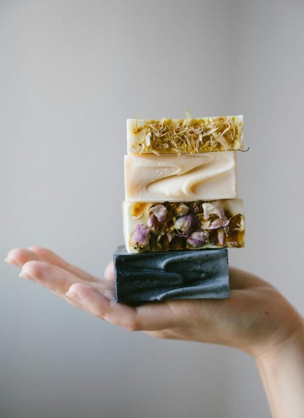 Stack of handmade organic soaps enhanced with dried flowers on an open hand.